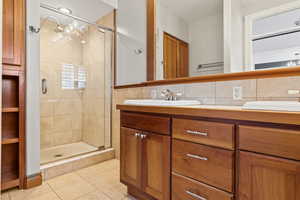 Primary full bath featuring tile walls, double vanity, light tile patterned flooring, and a shower stall and separate  tub