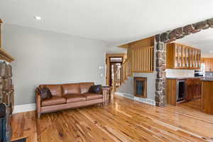 Family room with woord flooring, recessed lighting, a fireplace, beverage cooler, and stairway with built-in dog crate.