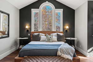 Primary bedroom  overlooking front woods, featuring wood finished floors and vaulted ceiling