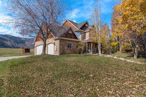 Craftsman-style home with a porch, stone and cedar exterior, a front lawn, concrete driveway, and an attached 3 car garage