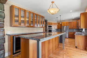 Kitchen with glass insert cabinets, decorative light fixtures, and wood flooring