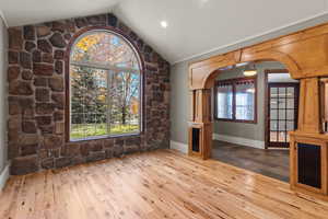 Front room with stone accent wall, arched walkways, wood flooring, lofted ceiling, and recessed lighting