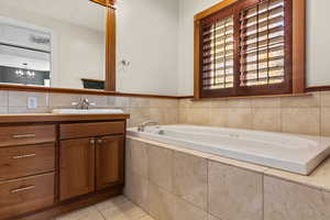 Primary full bathroom with vanity, a bath, a chandelier, and light tile floors