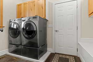 Laundry room featuring washing machine and clothes dryer and cabinet space and door to the garage
