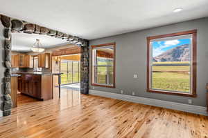 Kitchen featuring a breakfast bar, glass insert cabinets, wood flooring, stone archway, wood cabinets, pendant lighting and mountain views