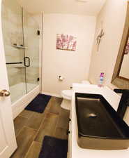 Full bathroom with shower / bath combination with glass door, vanity, and dark tile patterned flooring