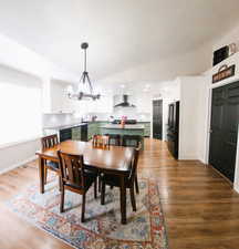 Dining space featuring vaulted ceiling, light wood finished floors, wine cooler, and a chandelier