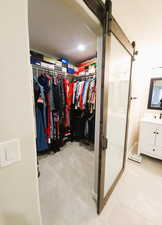 Walk in closet with a barn door and light tile patterned floors