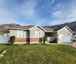 Single story home featuring a mountain view, stucco siding, stone siding, a garage, and driveway