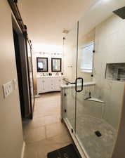 Full bathroom featuring double vanity, a shower stall, and light tile patterned floors