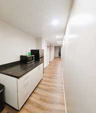 Kitchen with white cabinetry, light wood-style flooring, appliances with stainless steel finishes, dark countertops, and recessed lighting