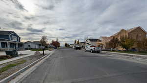 View of asphalt street with sidewalks, curbs, and a residential view