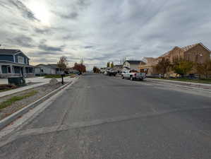 View of asphalt street featuring sidewalks, curbs, and a residential view