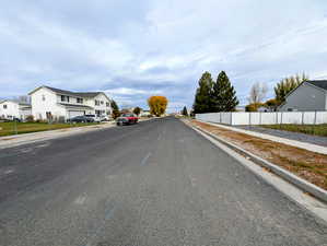 View of asphalt street featuring sidewalks, curbs, and a residential view