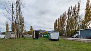 View of grassy yard featuring a storage unit and a mountain view
