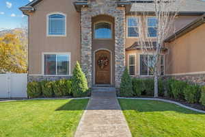 Doorway to property featuring stone siding, stucco siding, and a gate