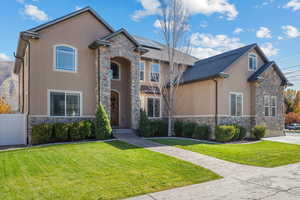 View of front facade with stone siding, stucco siding, and roof mounted solar panels
