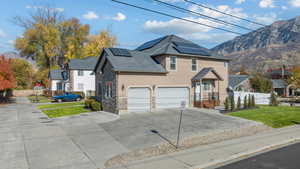 Traditional-style house featuring stone siding, a mountain view, concrete driveway, and a garage