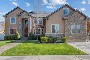 View of front of property with stone siding, stucco siding, and roof mounted solar panels