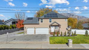Traditional-style house with driveway, roof mounted solar panels, stucco siding, and stone siding