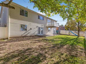 Rear view of house with a fenced backyard, a patio, a playground, and french doors