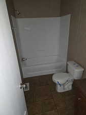 Bathroom featuring vanity, bathtub / shower combination, and dark tile patterned floors