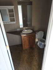 Half bathroom with vanity and dark tile patterned floors
