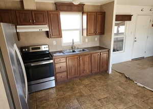 Kitchen with appliances with stainless steel finishes, brown cabinets, and under cabinet range hood