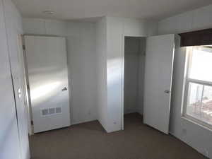 Unfurnished bedroom with a spacious closet and dark carpet