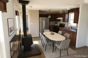 Kitchen with dark countertops, a wood stove, freestanding refrigerator, black / electric stove, and light tile patterned flooring
