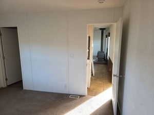 Unfurnished bedroom featuring light colored carpet, a closet, and a wood stove