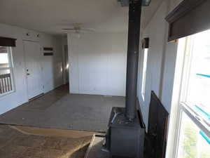 Unfurnished living room with a wood stove and a ceiling fan