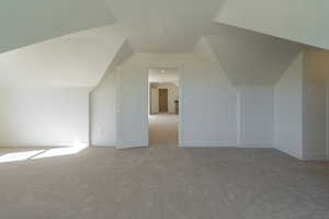 Bonus room with lofted ceiling and light carpet