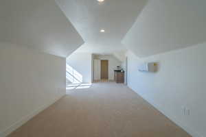 Bonus room with lofted ceiling, light carpet, recessed lighting, and a wall unit AC