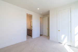 Unfurnished bedroom featuring light carpet, recessed lighting, and connected bathroom