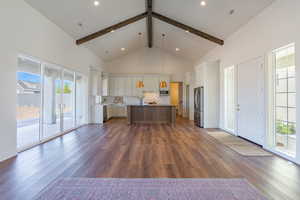 Kitchen with high vaulted ceiling, beam ceiling, pendant lighting, a kitchen island, and decorative backsplash