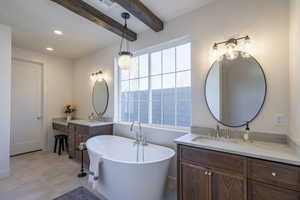 Full bathroom with a freestanding tub, two vanities, beam ceiling, and recessed lighting