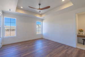 Spare room featuring a tray ceiling, dark wood finished floors, ceiling fan, and recessed lighting