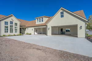 View of front of home with a shingled roof, concrete driveway, and stucco siding