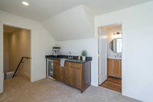 Bar with light colored carpet, wine cooler, vaulted ceiling, and recessed lighting