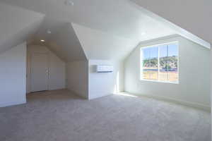 Additional living space featuring carpet flooring, vaulted ceiling, a wall mounted AC, and recessed lighting