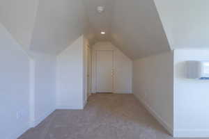 Bonus room featuring light carpet, vaulted ceiling, a wall unit AC, and recessed lighting