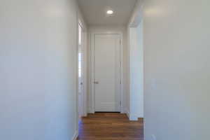 Corridor with dark wood-style flooring and recessed lighting