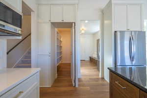 Kitchen with appliances with stainless steel finishes, dark wood-style flooring, dark stone countertops, white cabinets, and recessed lighting