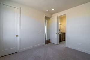Unfurnished bedroom featuring light carpet, connected bathroom, and recessed lighting
