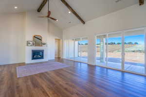 Unfurnished living room featuring high vaulted ceiling, beam ceiling, a glass covered fireplace, dark wood-style floors, and recessed lighting