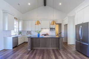Kitchen with stainless steel appliances, tasteful backsplash, beam ceiling, pendant lighting, and dark wood finished floors