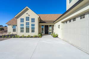 View of front of house with a shingled roof, stucco siding, and driveway