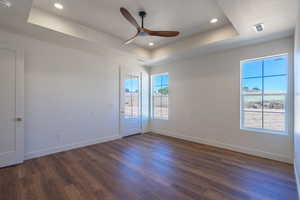 Spare room featuring a raised ceiling, dark wood-style floors, recessed lighting, ceiling fan, and a smoke detector
