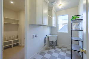 Washroom with light floors, hookup for a washing machine, cabinet space, and electric dryer hookup